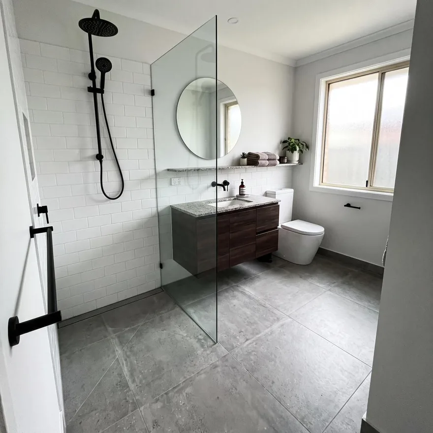 A finished bathroom with white subway tile, matte black fixtures, a walk-in shower and a floating wood vanity